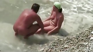 Voyeur tapes a milf jerking and sucking her man on a nude beach